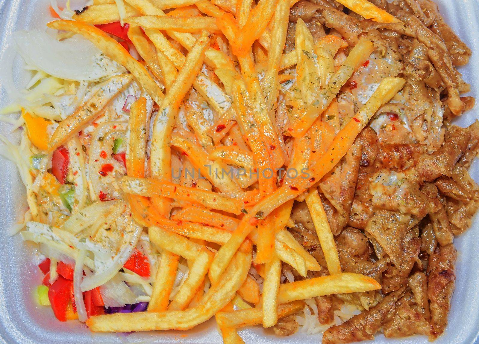 Lunch Box: kebabs, fries and fresh salad in tray. Close-up on the table. Unhealthy food concept. 