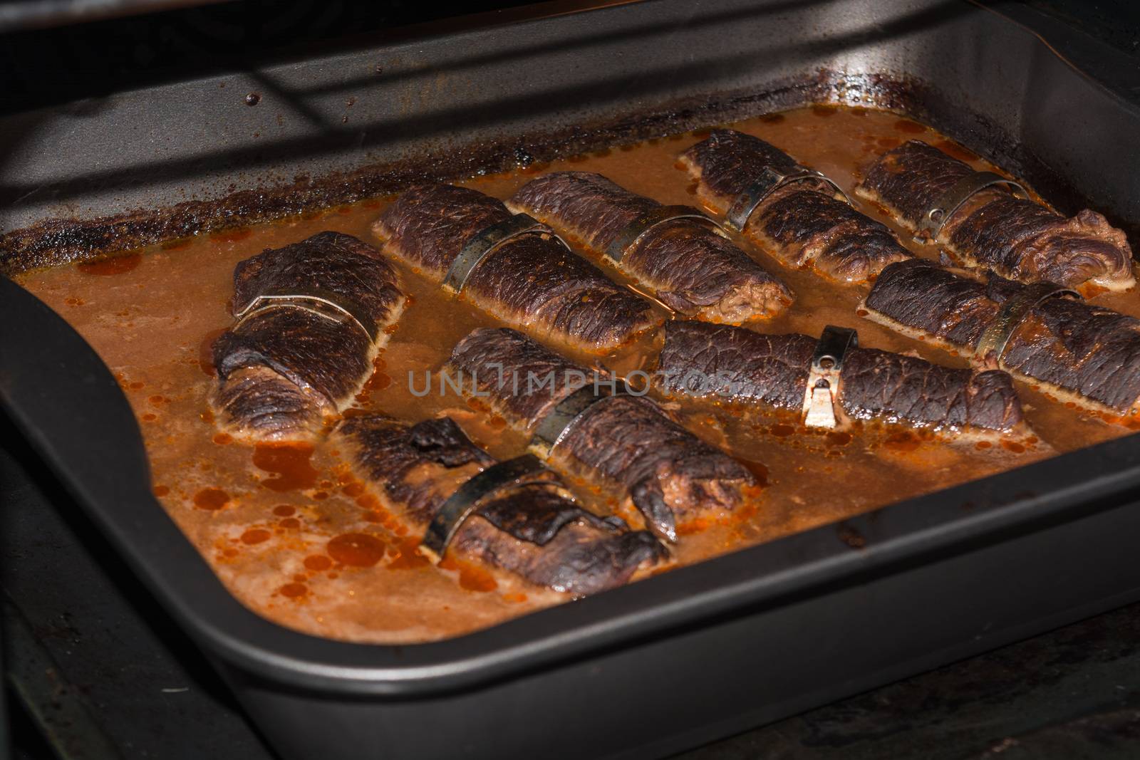 Fresh beef roulades braised in a dish in the oven.