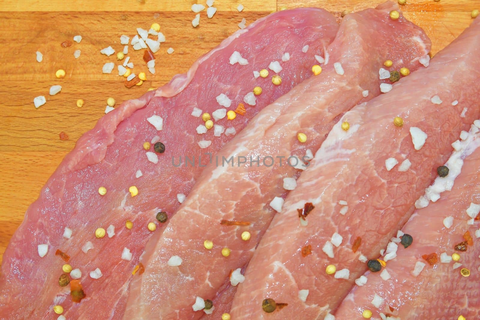 Raw pork loin chops on a cutting board with spices.  Pork chops with spices on a cutting board. Slices of pork steaks. Pork chops ready to fry. Selective focus. by roman_nerud