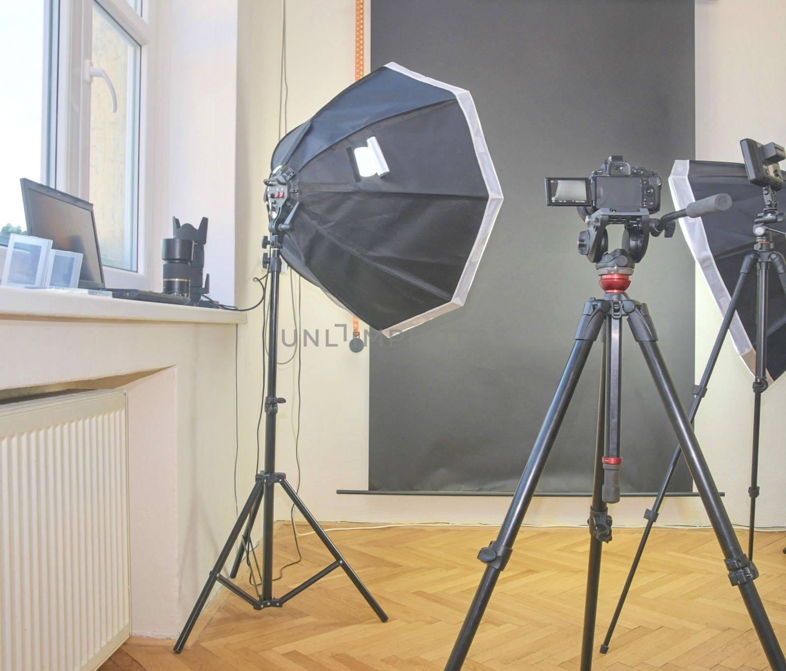 Empty photo studio with lighting equipment. Professional camera, lenses and filters for photographer by roman_nerud