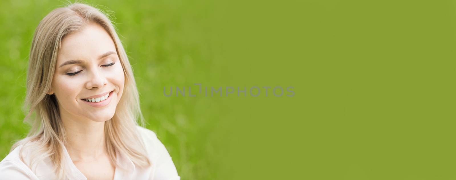 A beautiful young woman on grass enjoy nature smiling with closed eyes, green copy space, for text