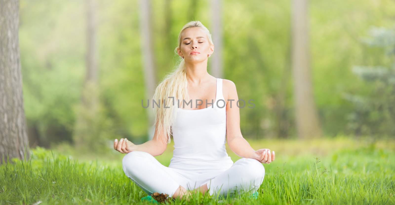 Young girl doing lotus yoga exercise in spring park