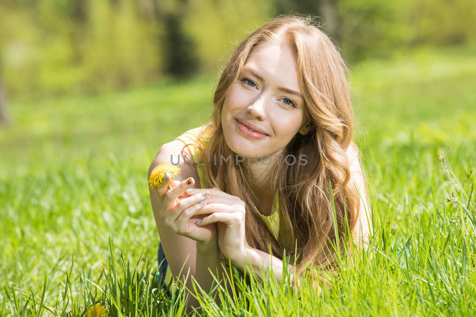 Redhead or blonde romantic beautiful young woman laying on grass in park