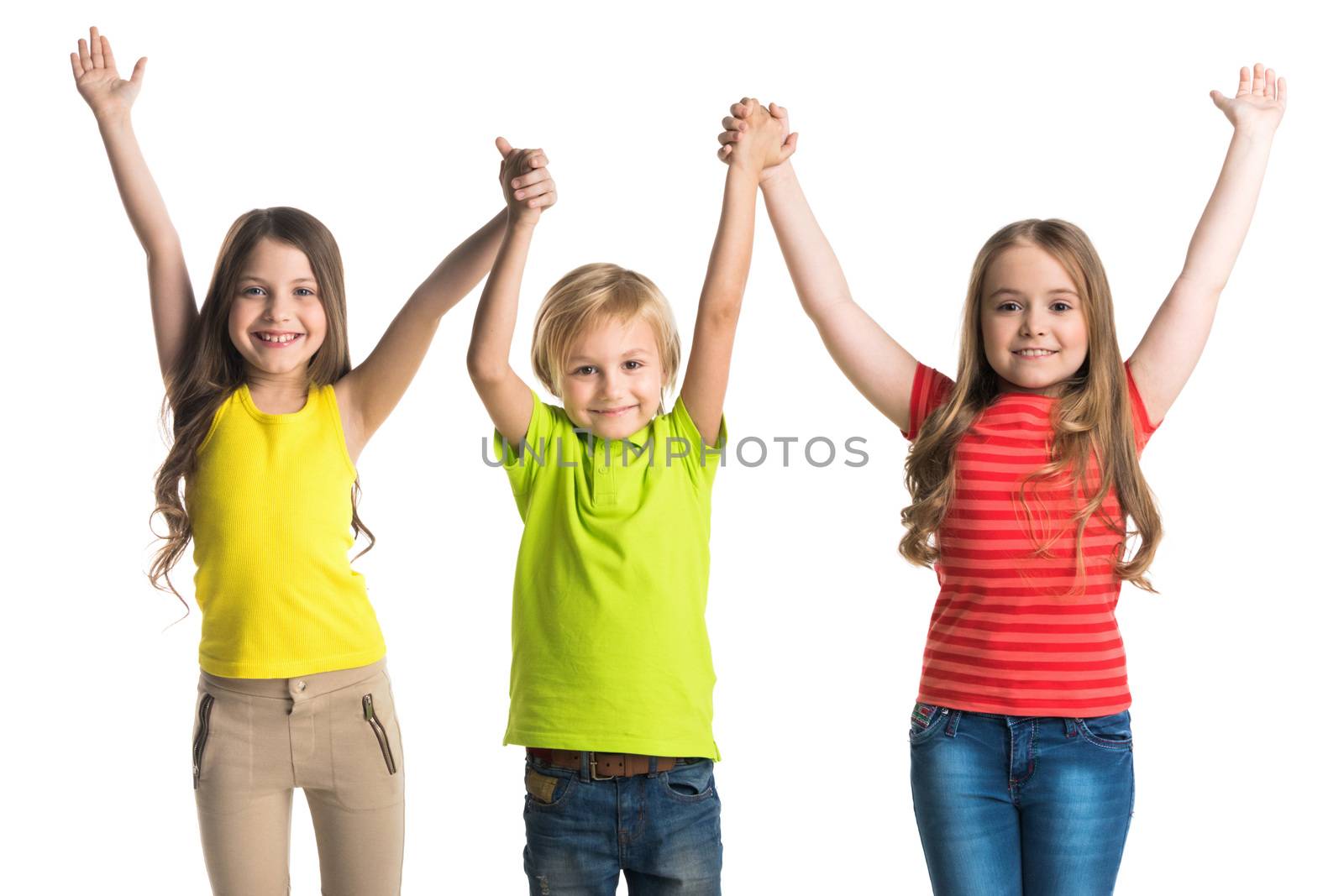 Happy smiling three children in colorful clothes holding raised hands isolated on white background