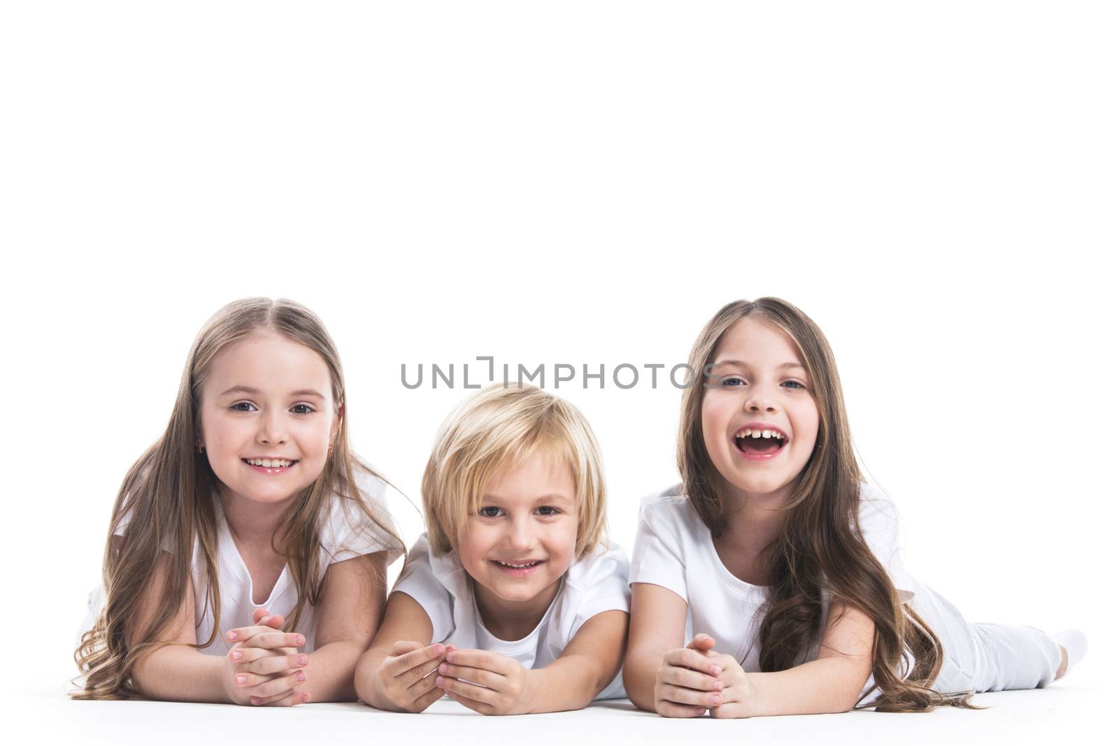 Happy smiling three children in white clothes laying on floor isolated on white background