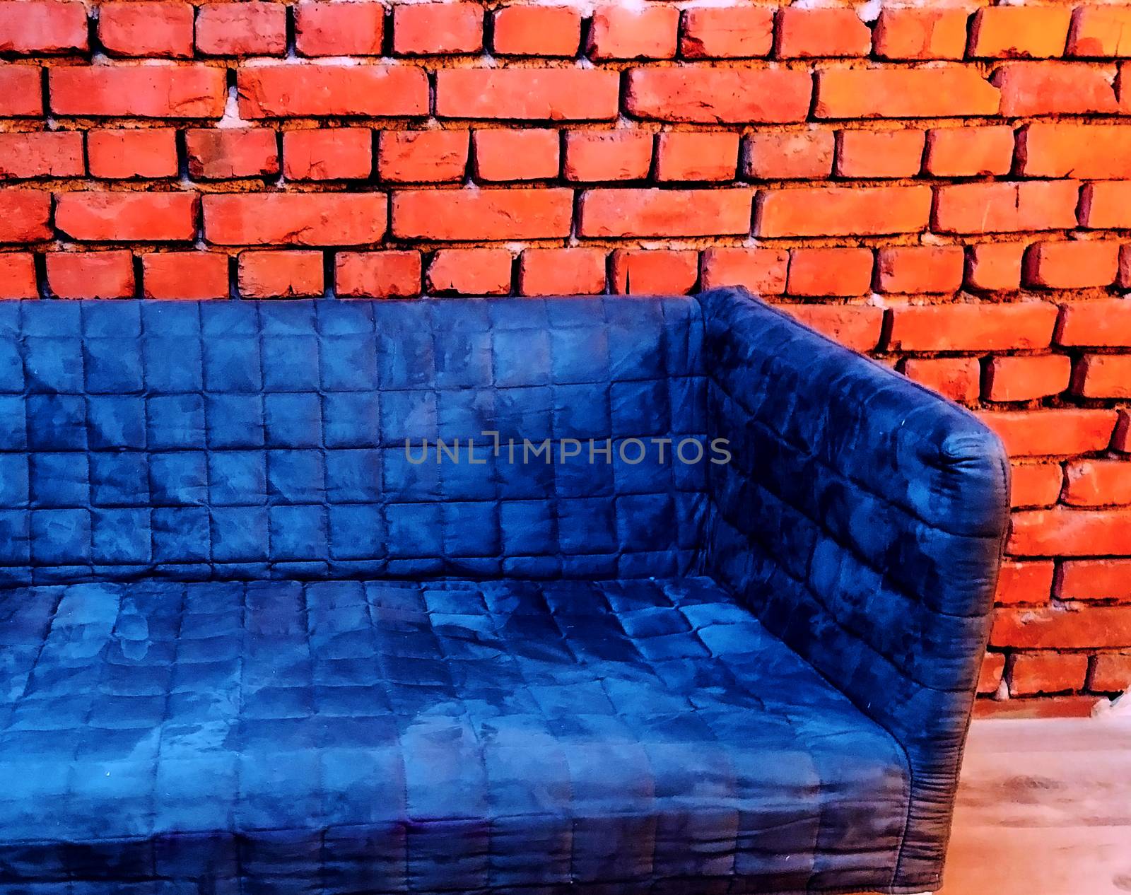 plush puff blue sofa on a brick backgrund vintage industrial style indoor concept
