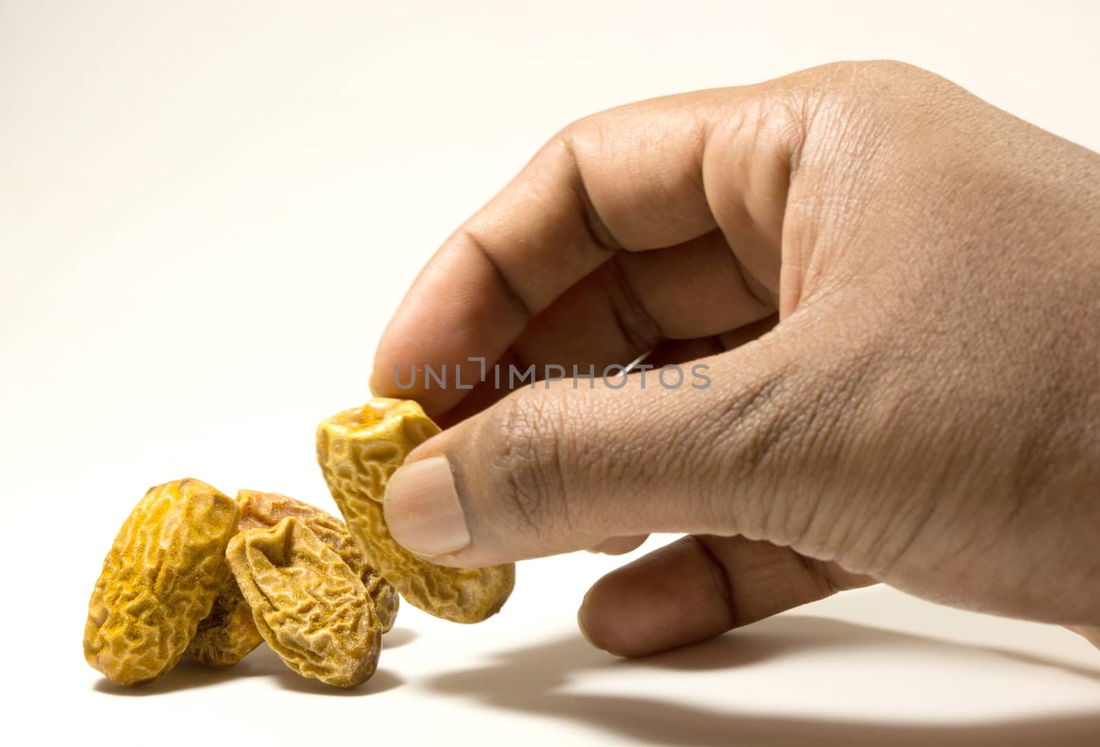 Dry Dates picking with hand isolated on white background by lakshmiprasad.maski@gmai.com