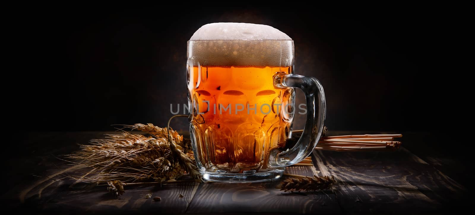 Beer in mug and wheet on wooden table and black background