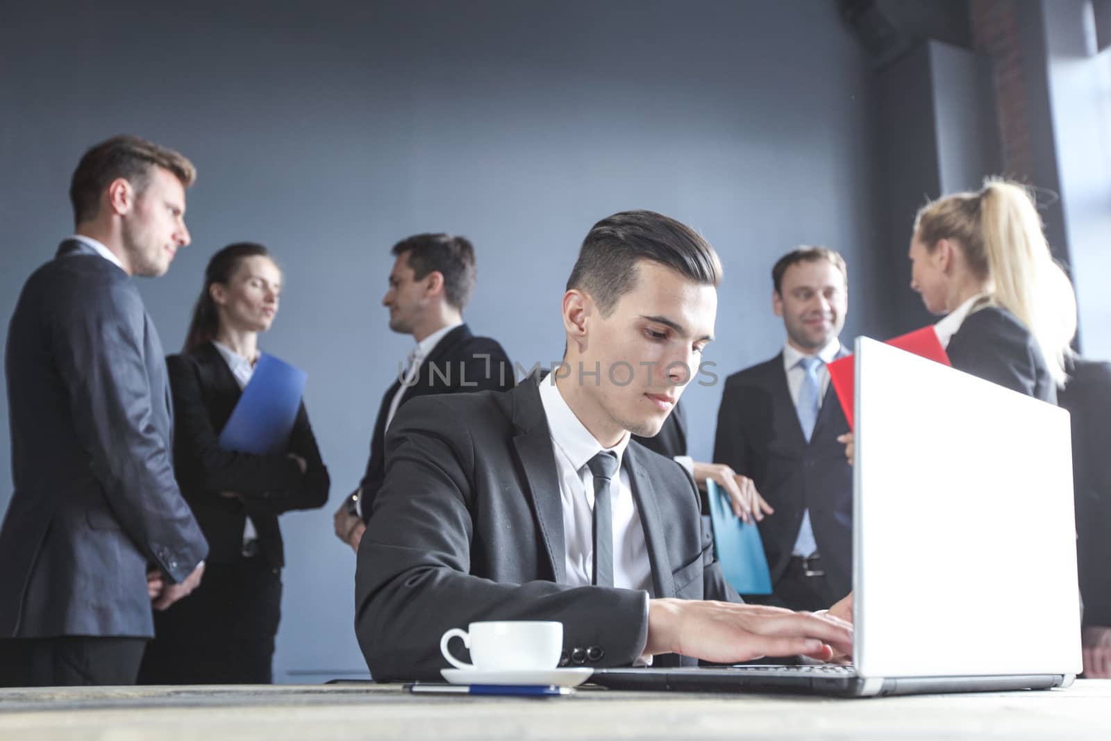Business man working with laptop, team of coworkers on background