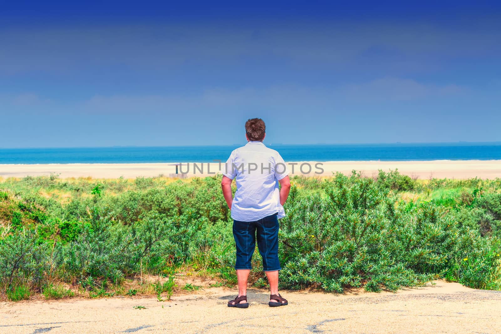 Man stands on the beach and looks out to sea
