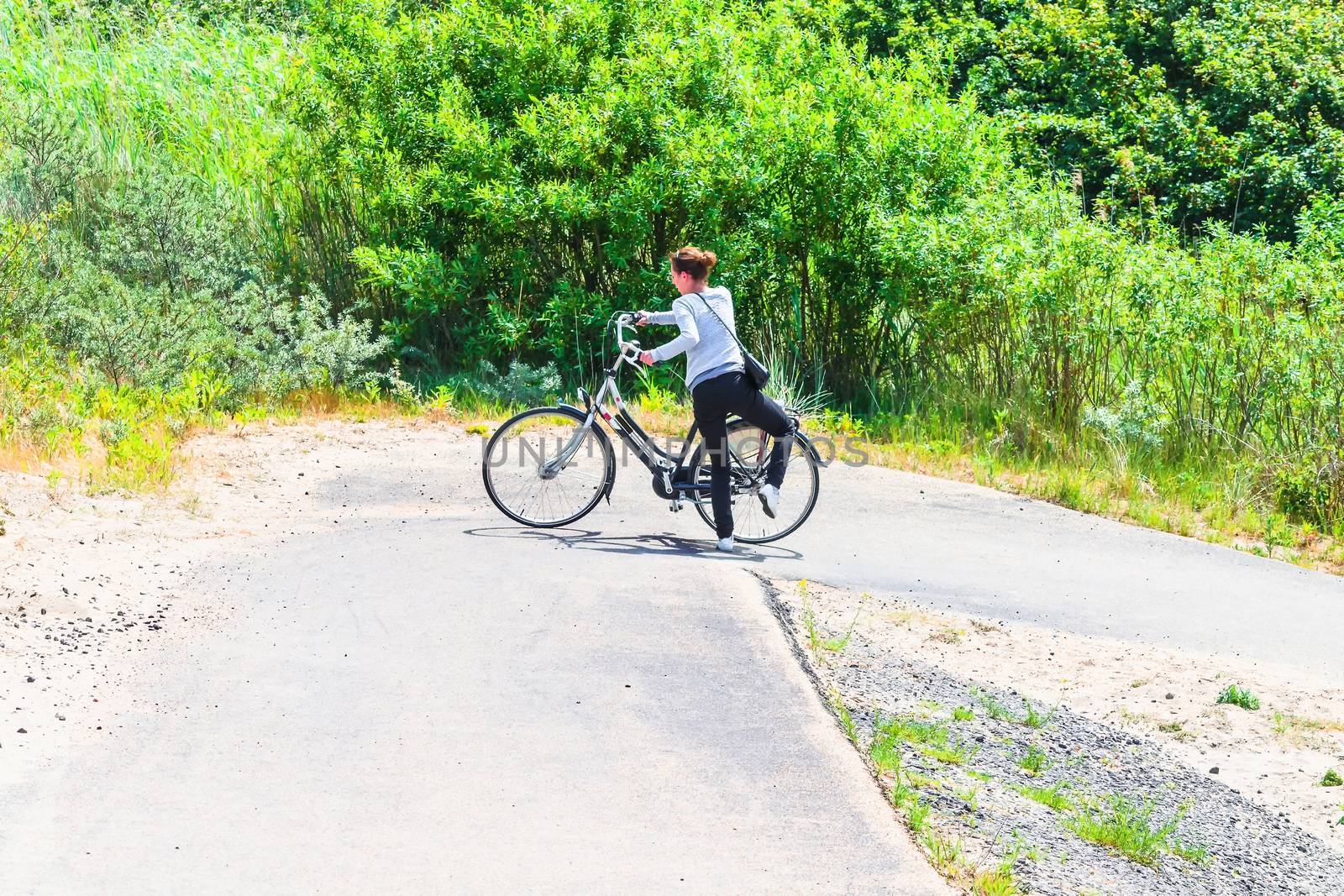 Young woman with the E-bike on a sunny day.            by JFsPic