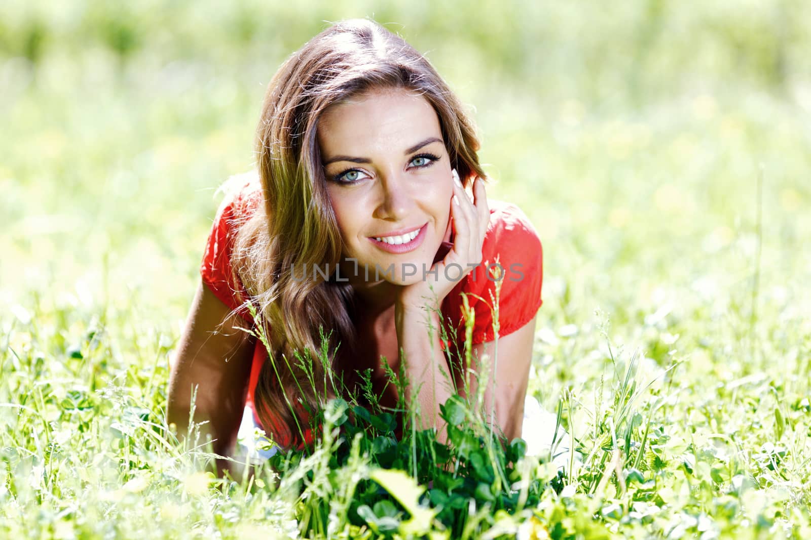 beautiful young woman in red dress lying on grass
