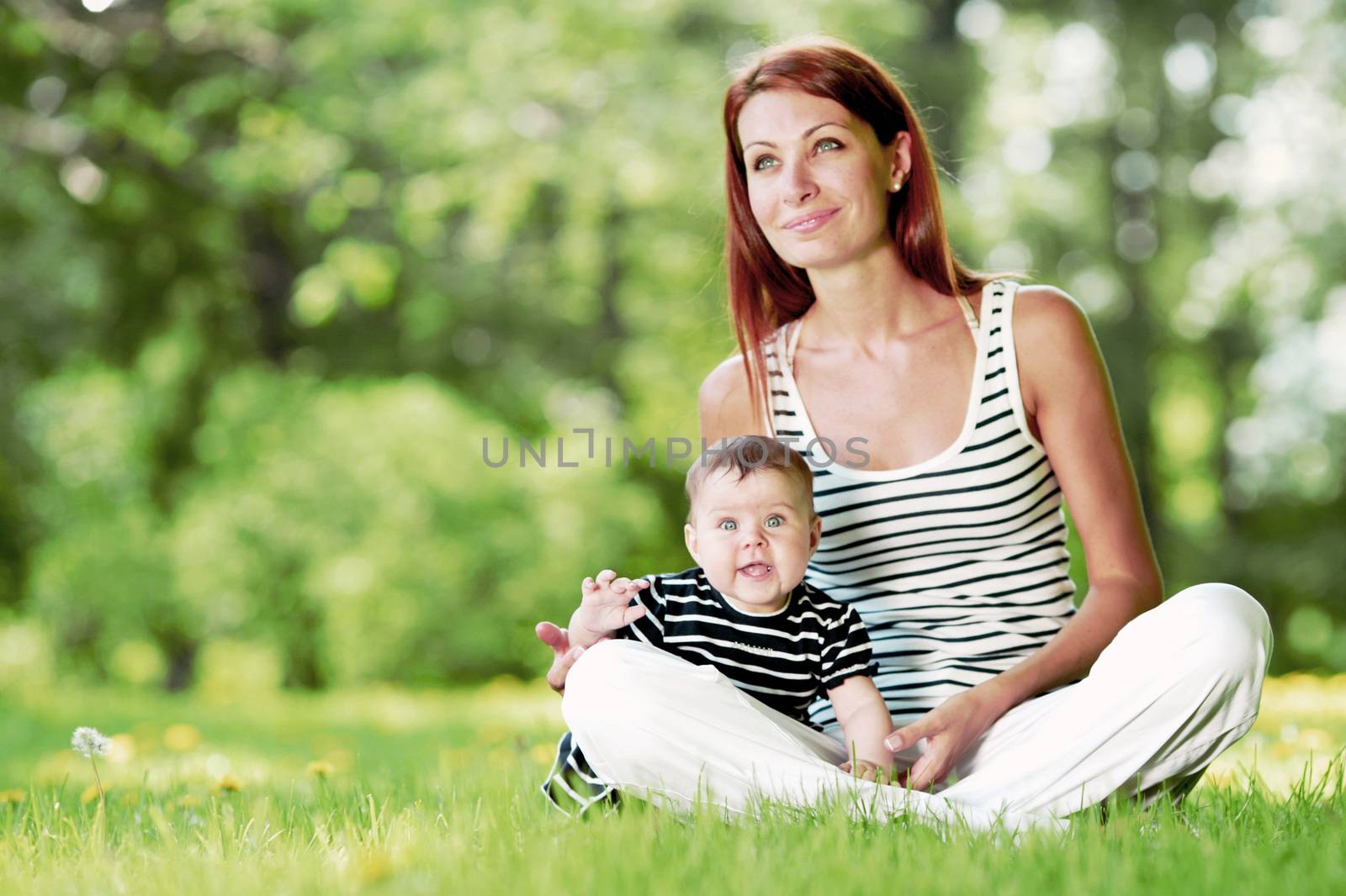 Mother and daughter sitting on grass in spring park