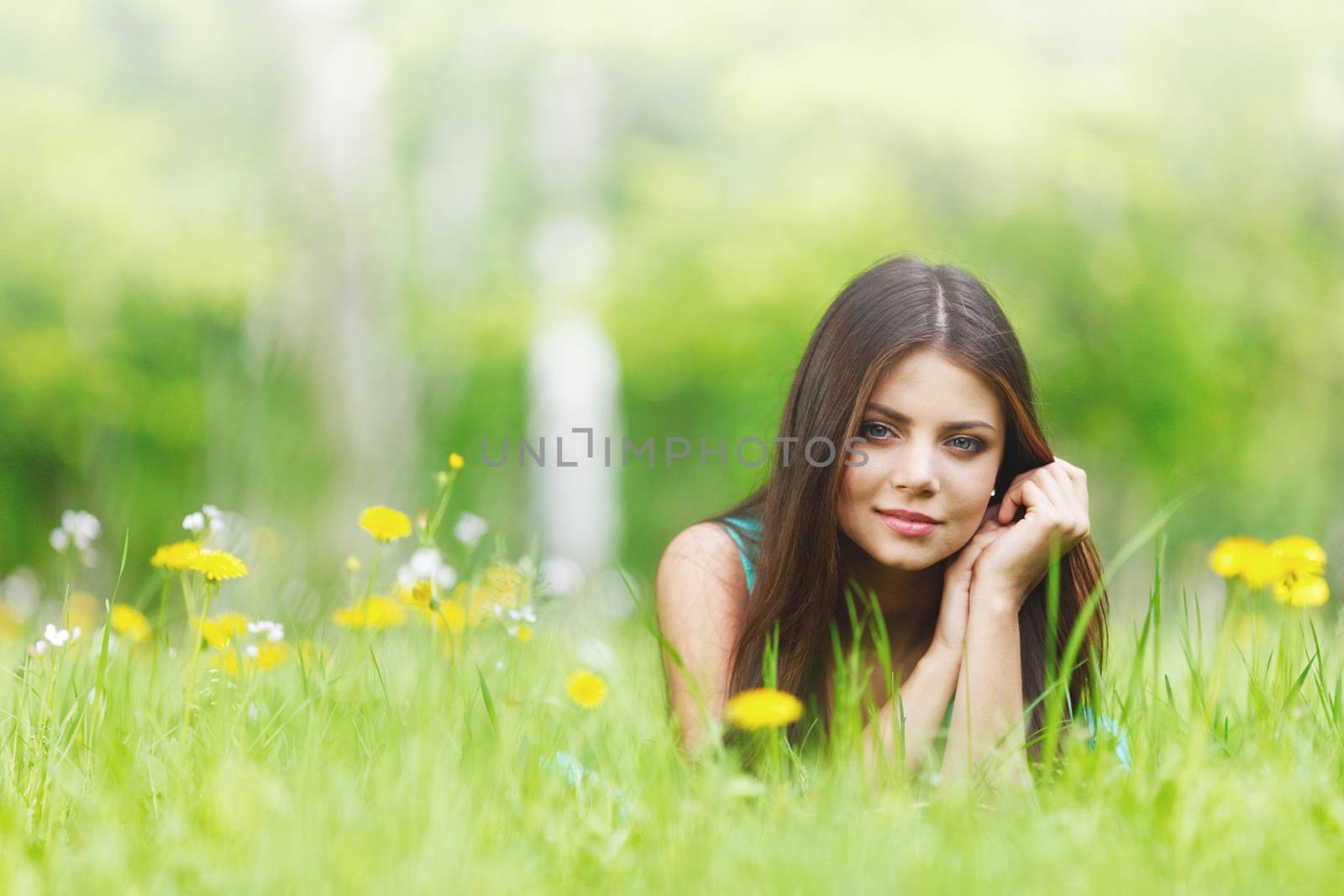 Young beautiful woman resting on fresh green grass with flowers