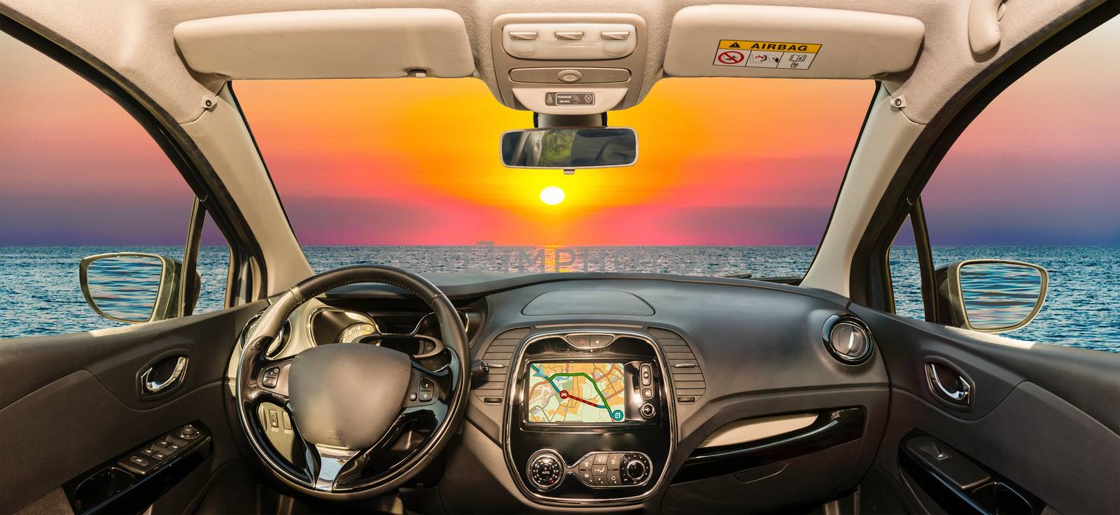 Looking through a car windshield with view over a scenic sunset on the mediterranean sea