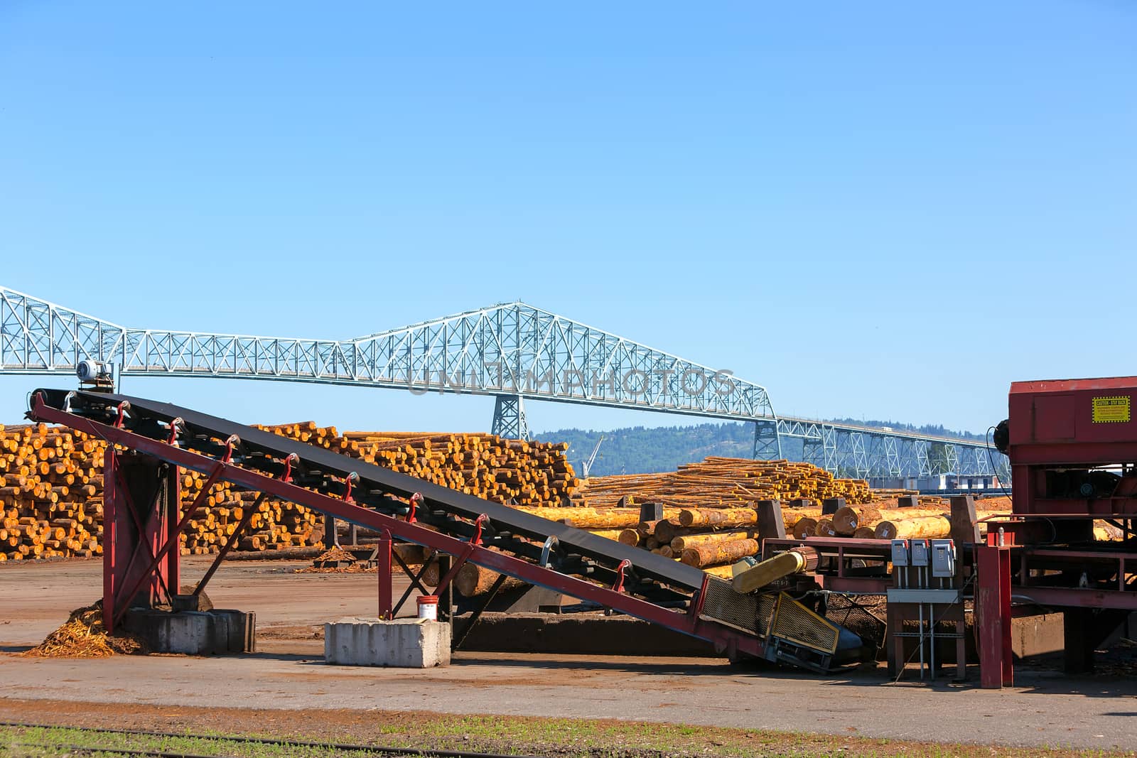 Lumber Mill in Rainier Oregon with logs and machinery by Columbia River Longview Bridge