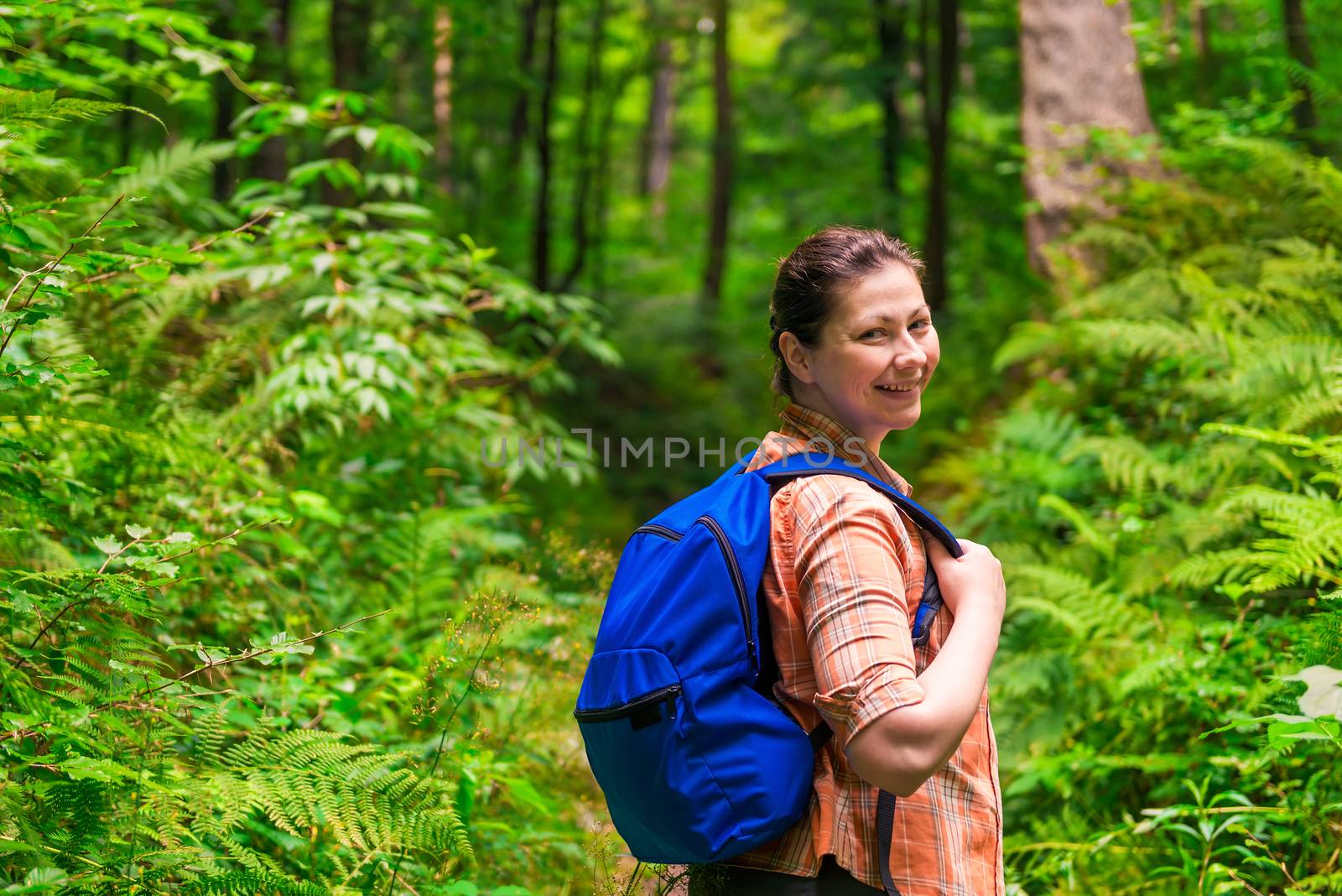 happy woman with a backpack strolling through the park