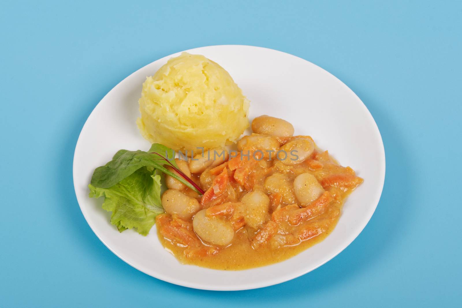 Beans with carrots and potatoes on a blue background