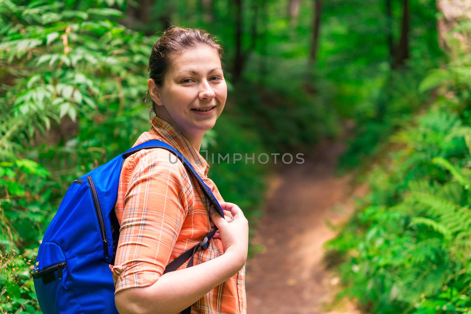 portrait of a woman with a backpack in a green forest in a hike