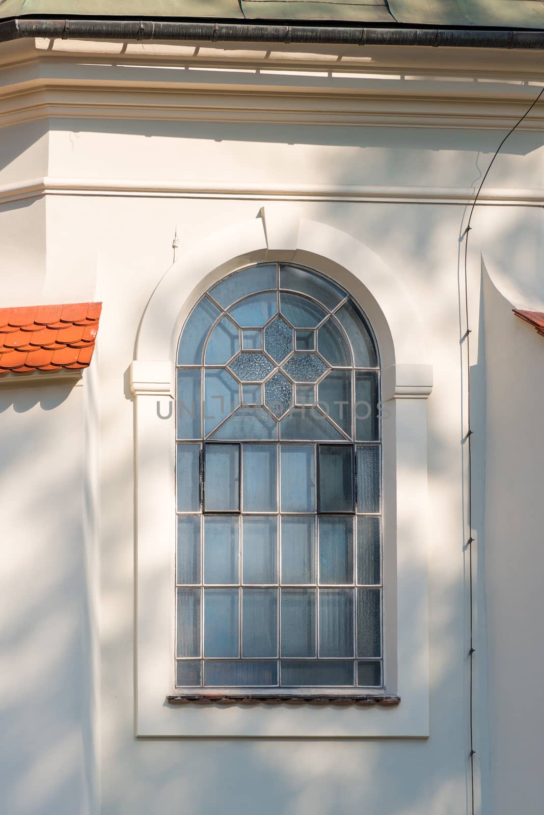 a window with an arch and a lattice, a white wall of a building