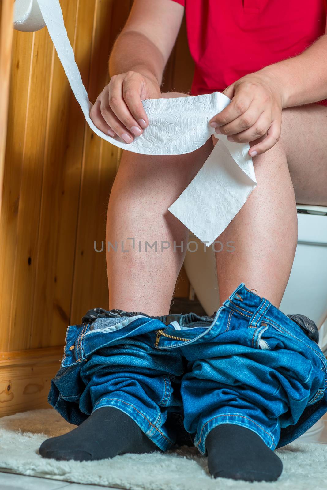 concept photo - a man in a toilet tears off toilet paper