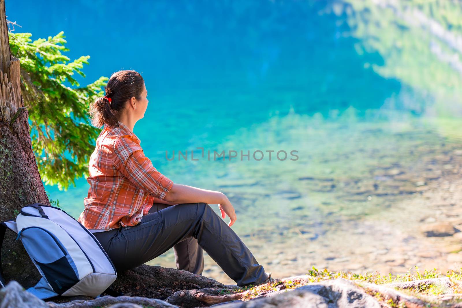 a woman sits by the Lake of the Sea Eye in the Tatra Mountains and admires