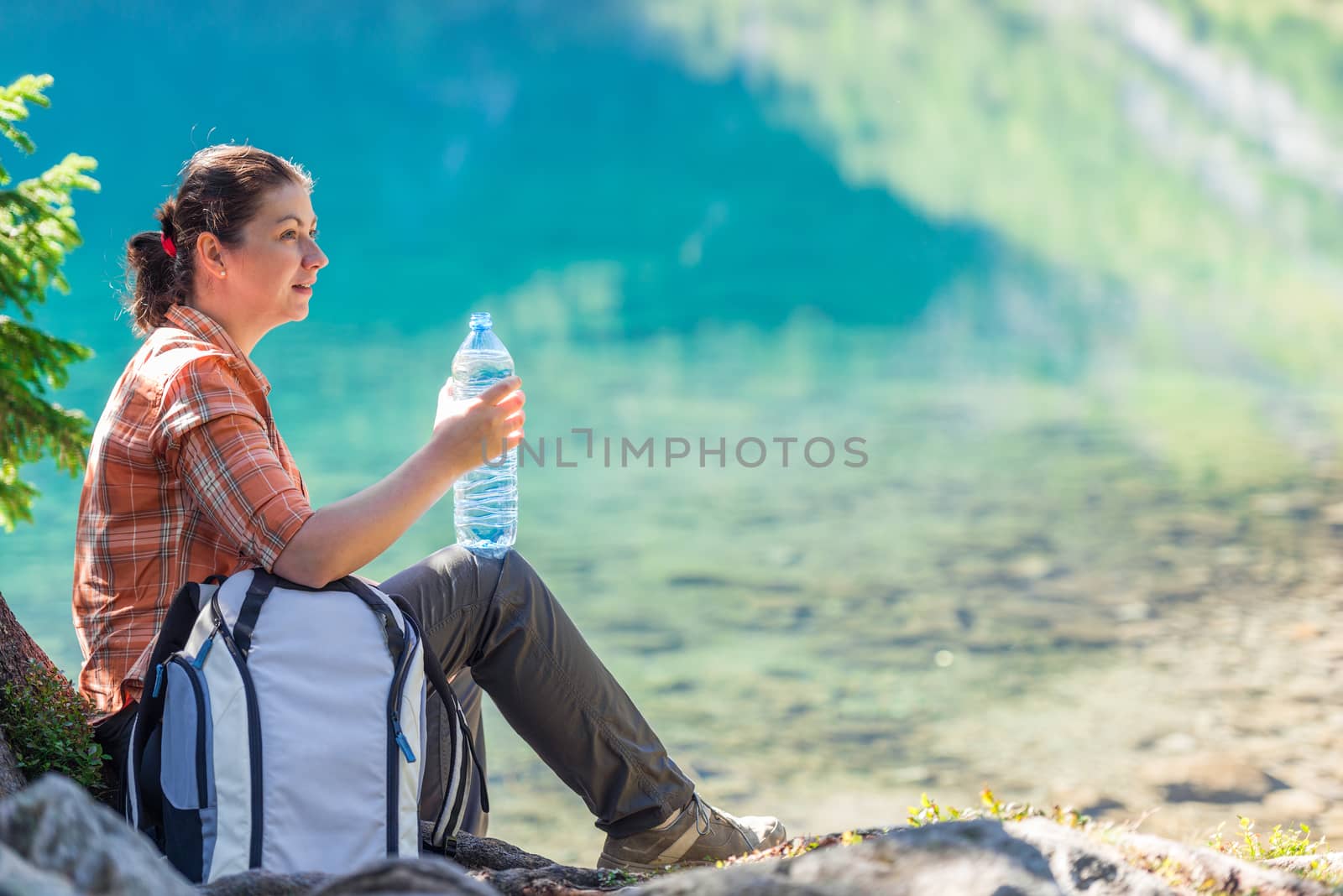 girl tourist with a bottle of water admiring a beautiful mountai by kosmsos111