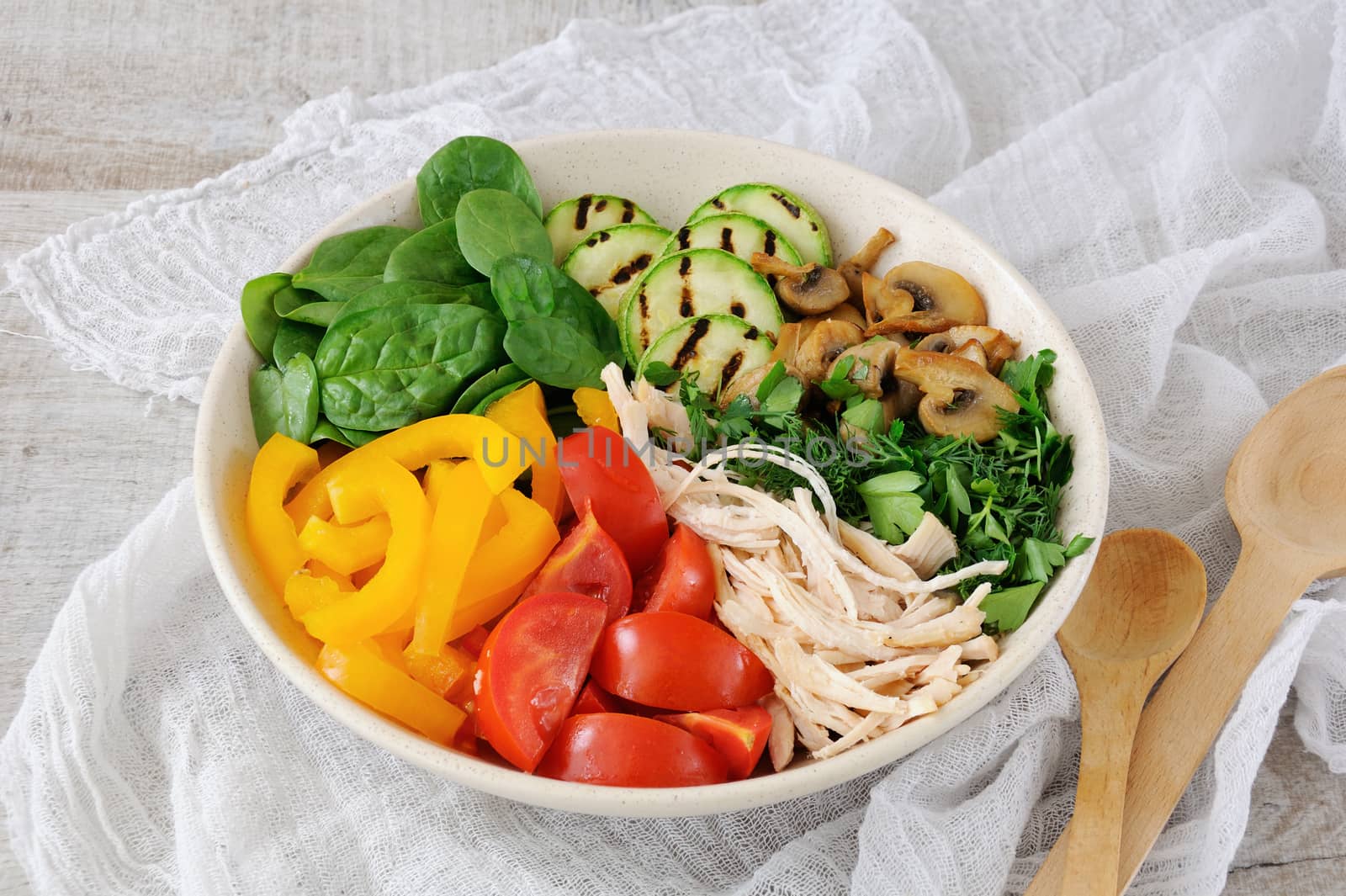 Warm chicken salad with spinach, tomato slices, sweet pepper, grilled zucchini, and champignons