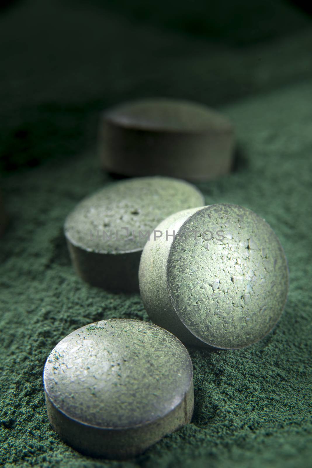 Close up of spirulina tablets on powder background with low depth of field. Vertical image.