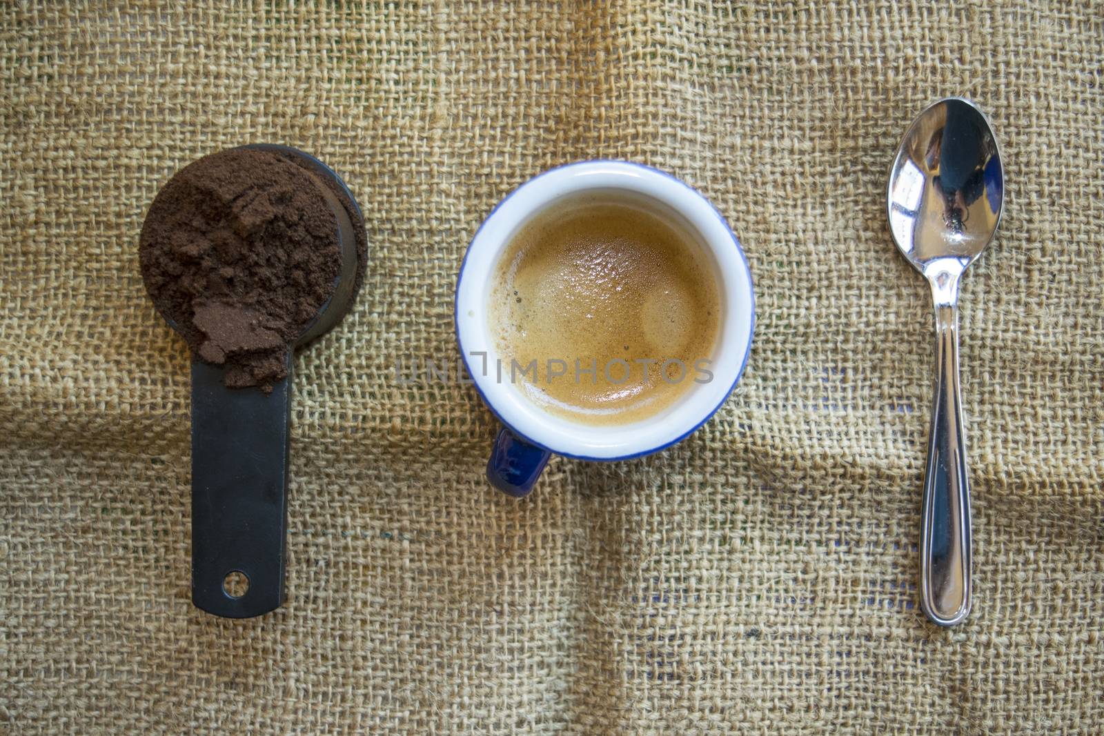 measuring scoop of ground coffee next a cup of expresso coffee