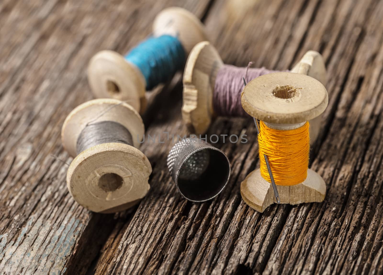 colored threads and thimble on wooden background