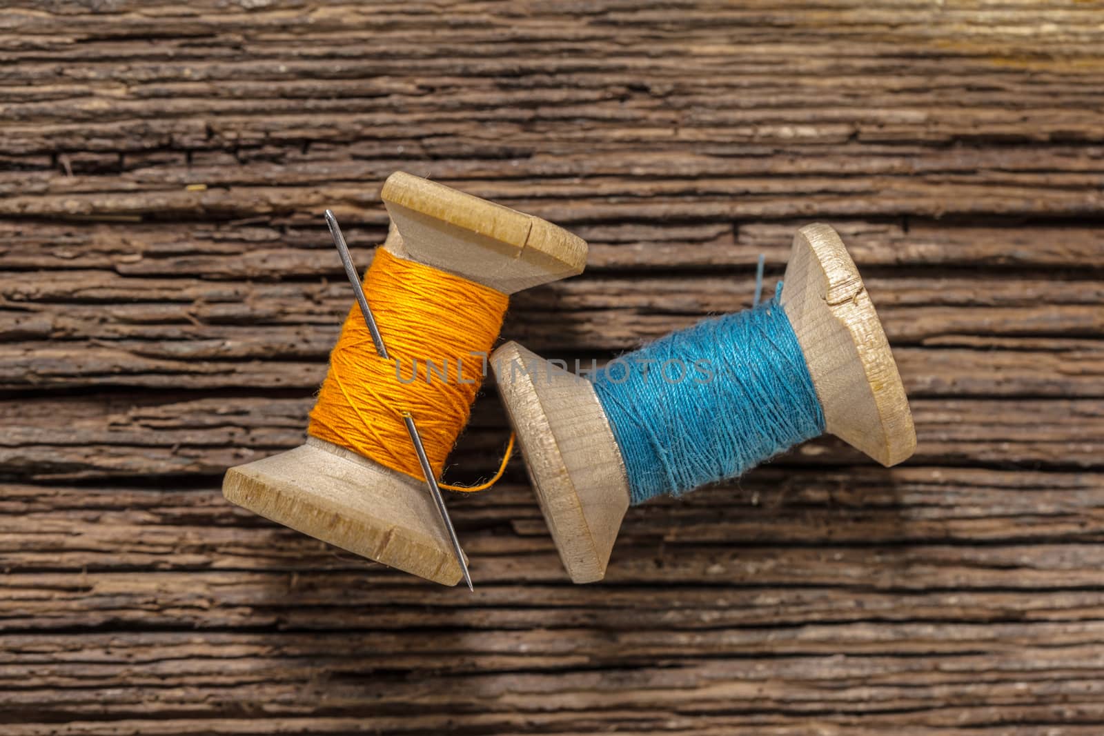 colored threads and needle on wooden background