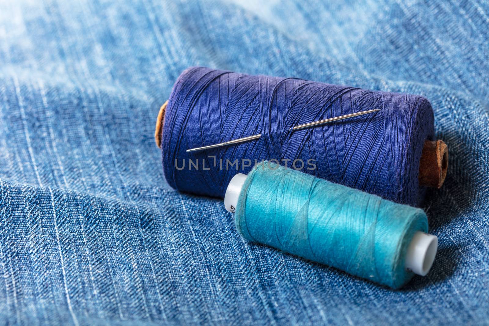 blue threads with needle on the background of denim