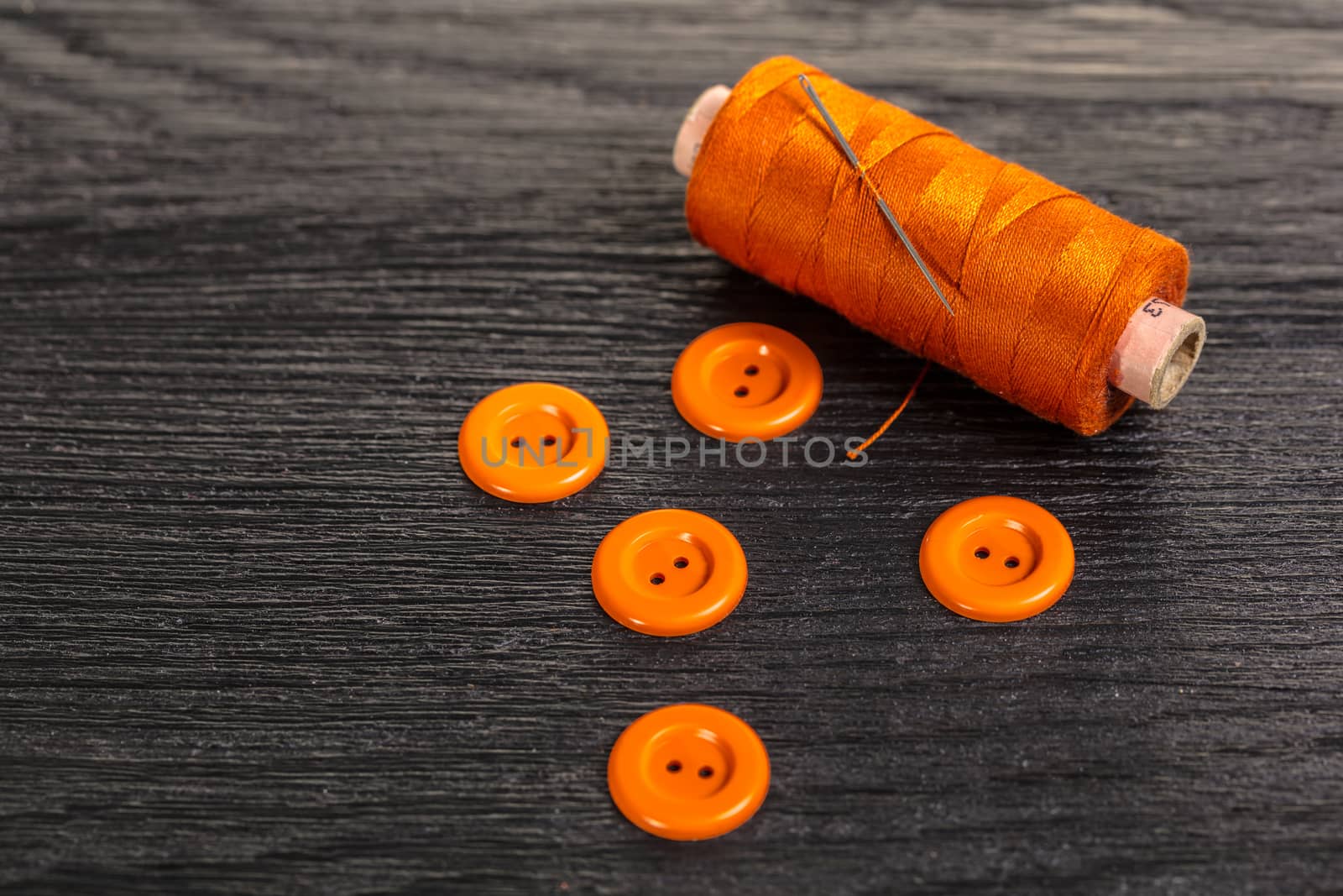 spool of threads and buttons on a wooden background