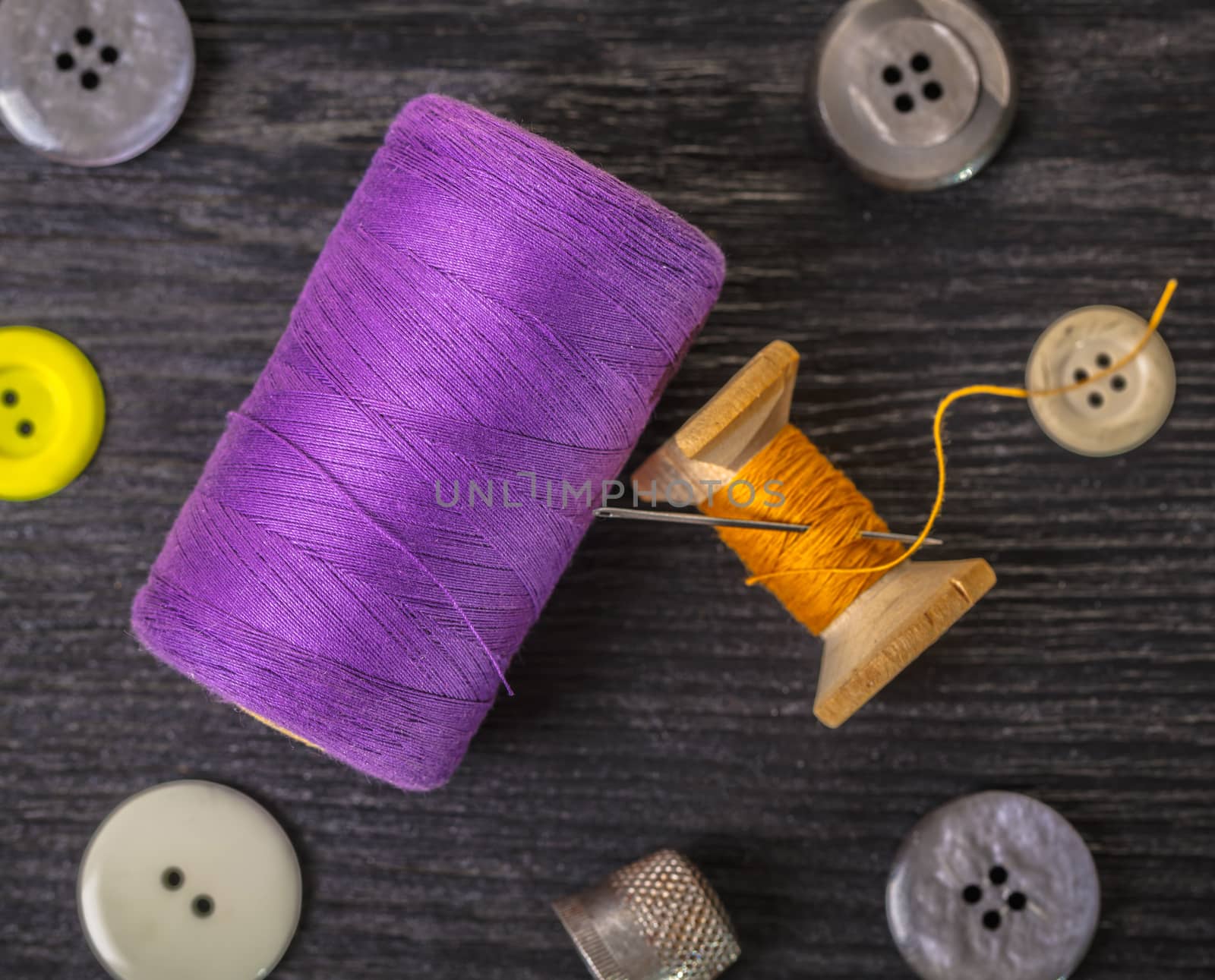 spool of threads and buttons on a wooden background