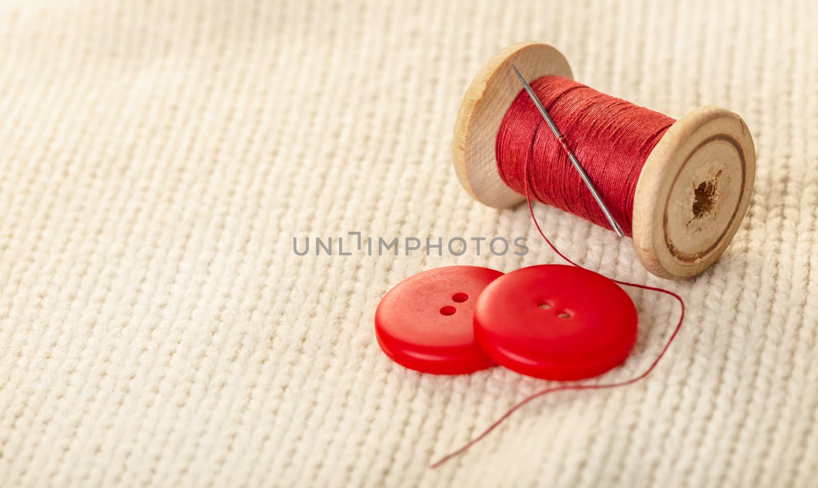 colored thread and buttons on white knitted fabric