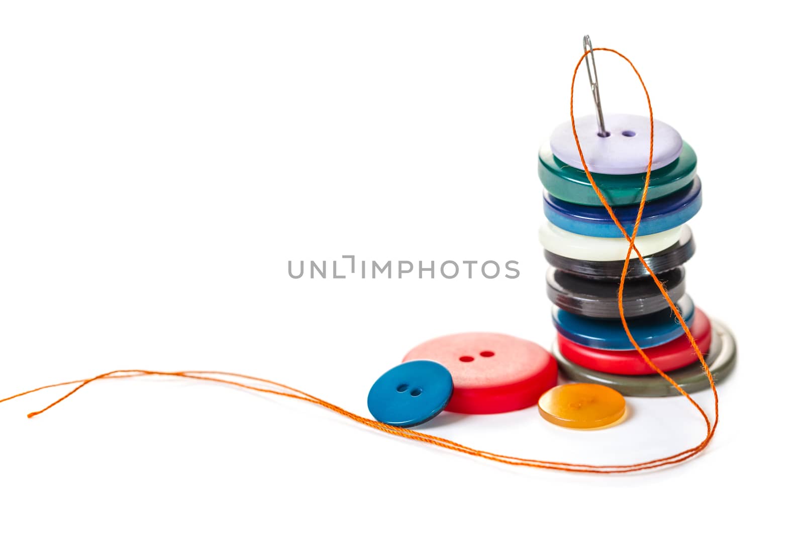 Needle with orange thread and buttons on a white isolated background