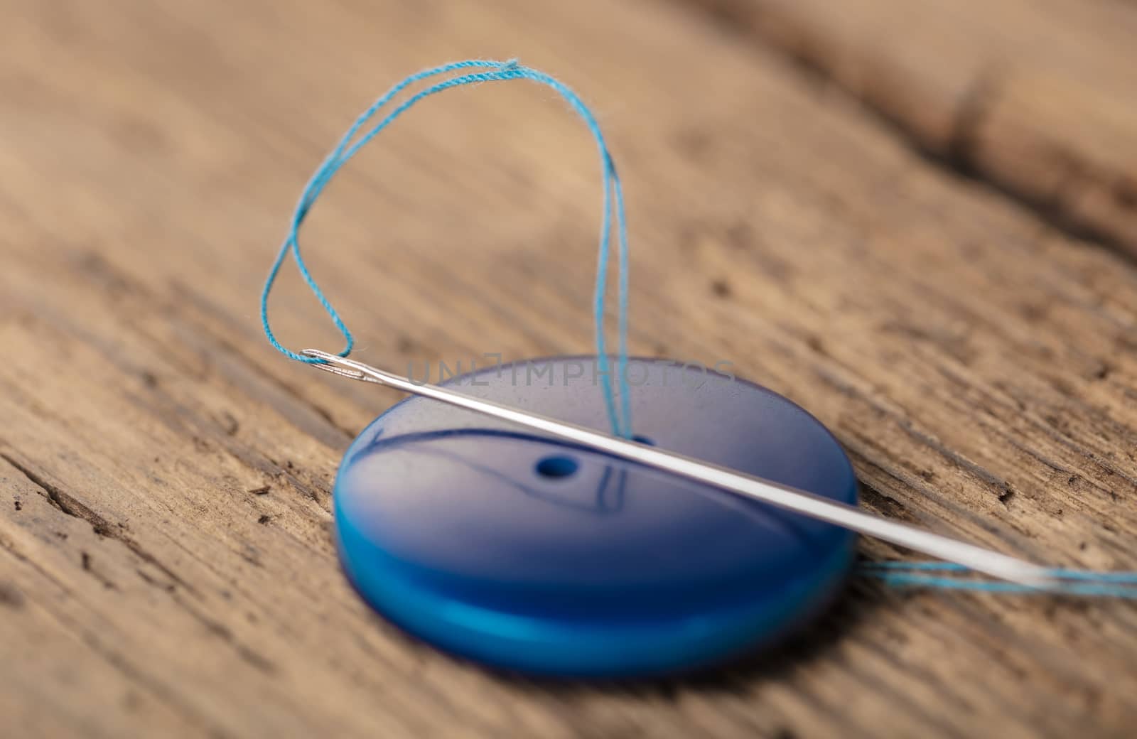 blue button with needle close-up on a wooden background