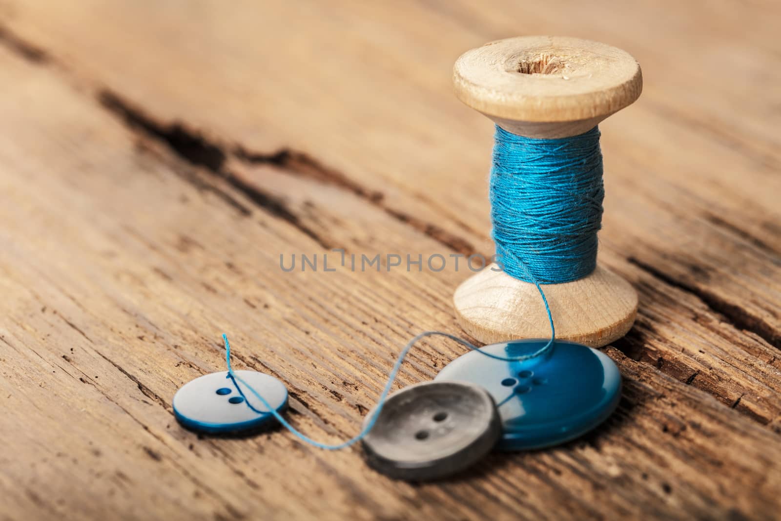 spool of threads and buttons on a wooden background