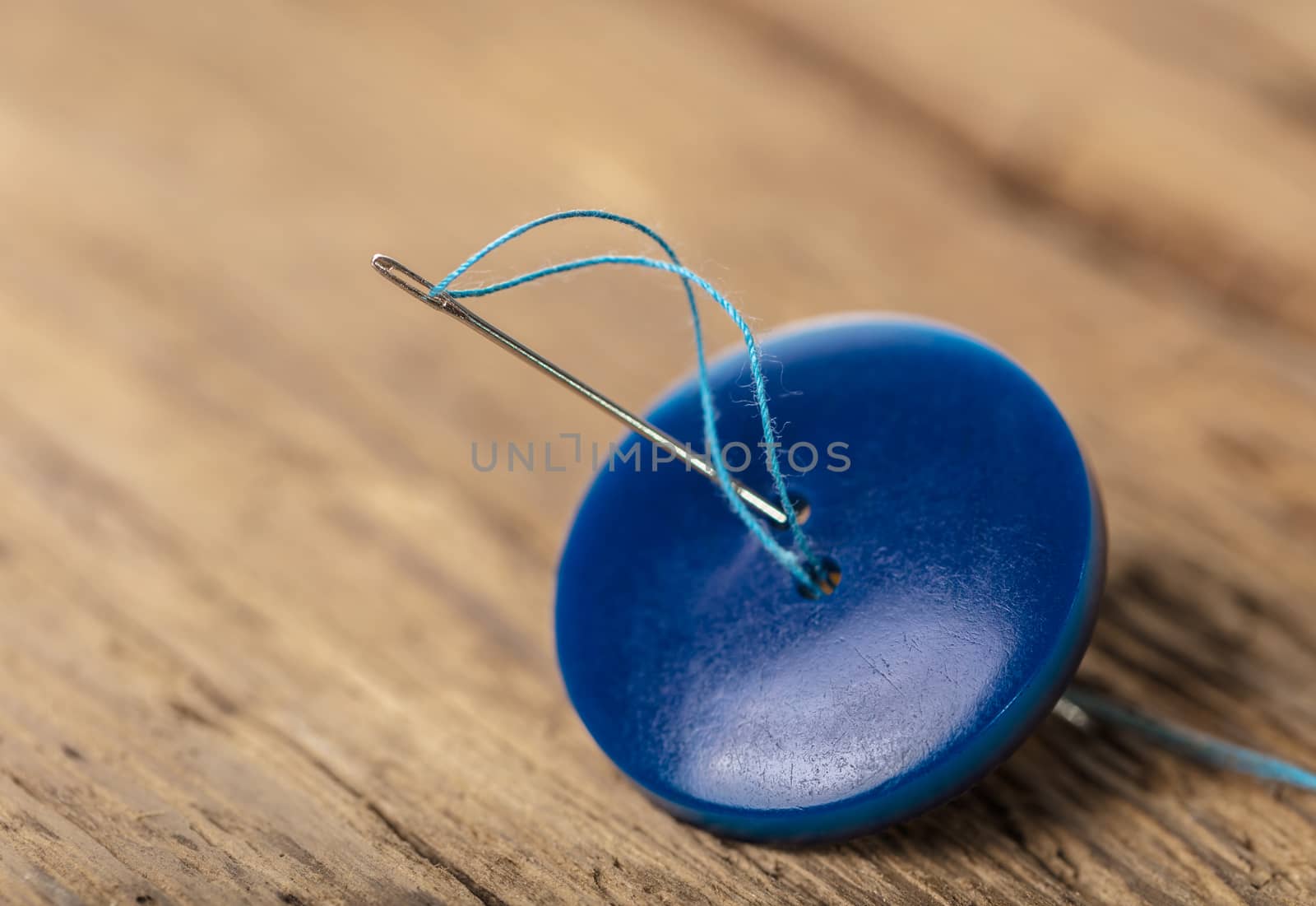 blue button with needle close-up on a wooden background