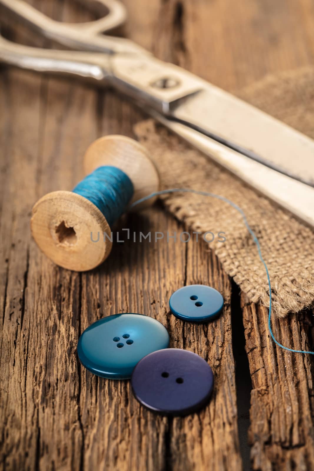 blue thread with buttons and scissors, wooden background