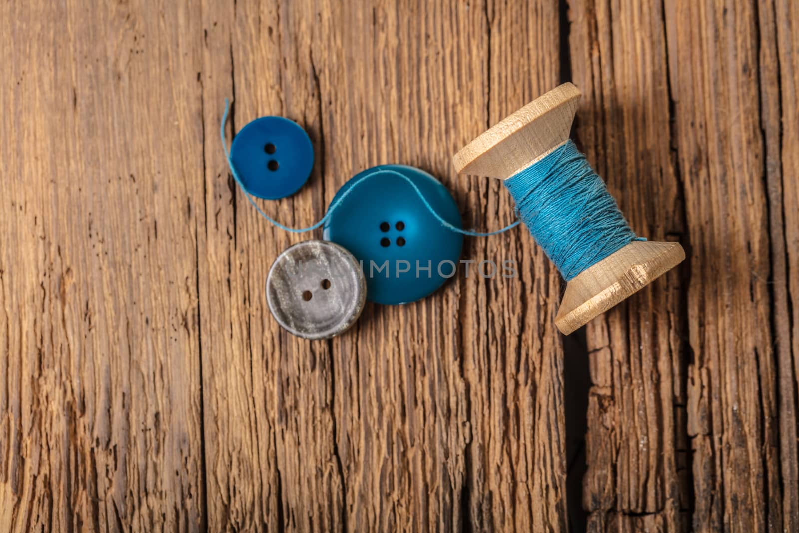 spool of threads and buttons on a wooden background