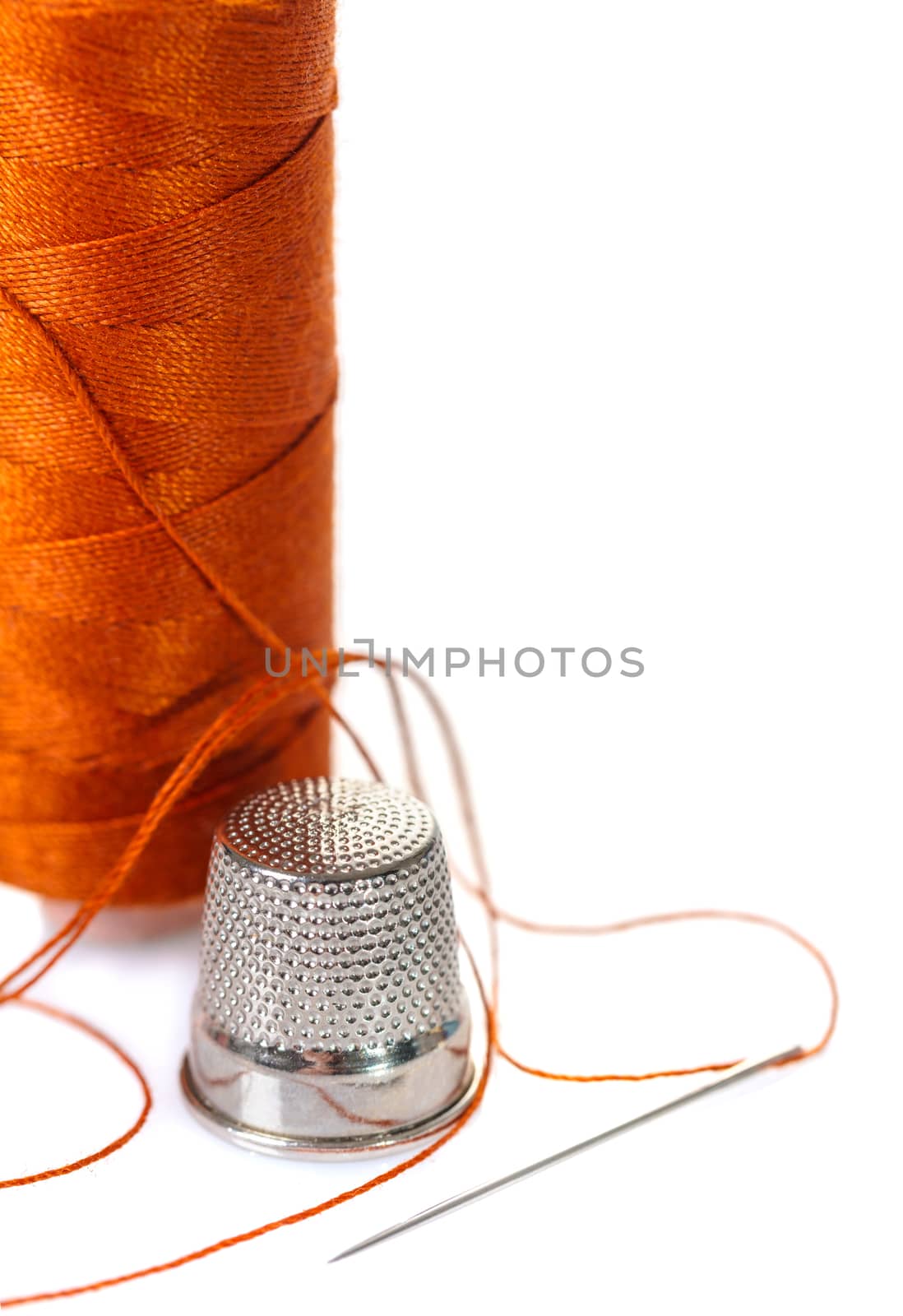 needle with an orange thread and a thimble on white background