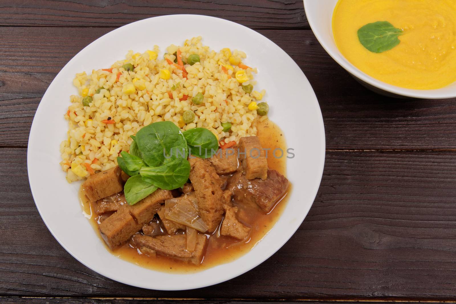 Tempeh with tomato sauce and millets on a wooden table