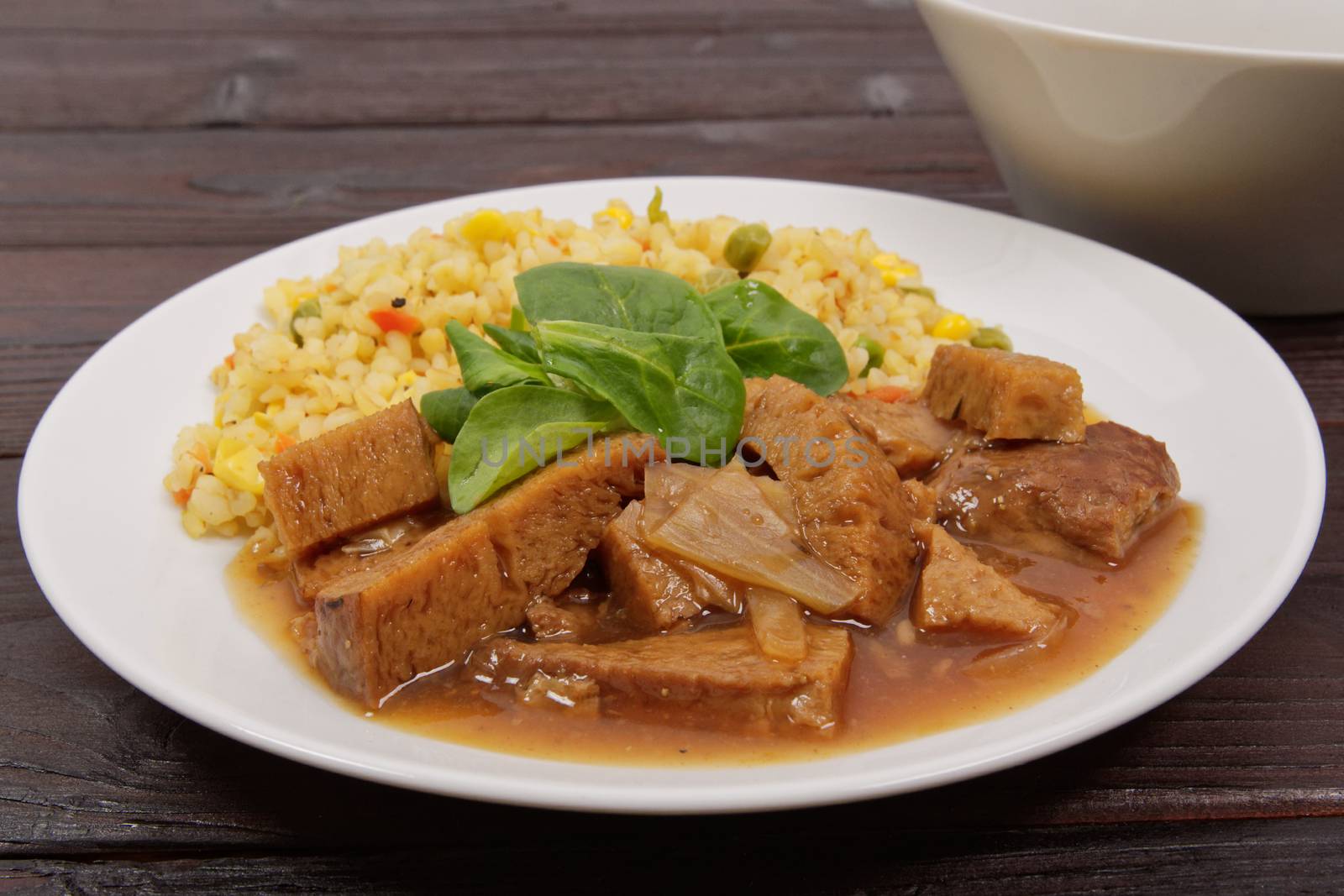 Tempeh with tomato sauce and millets on a wooden table