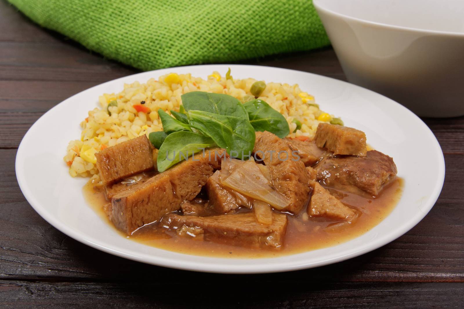 Tempeh with tomato sauce and millets on a wooden table