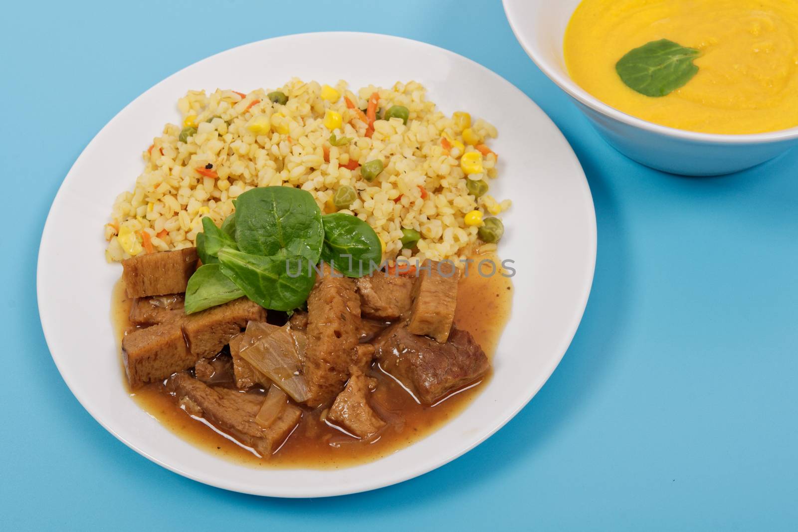 Tempeh with tomato sauce and millets on a blue background