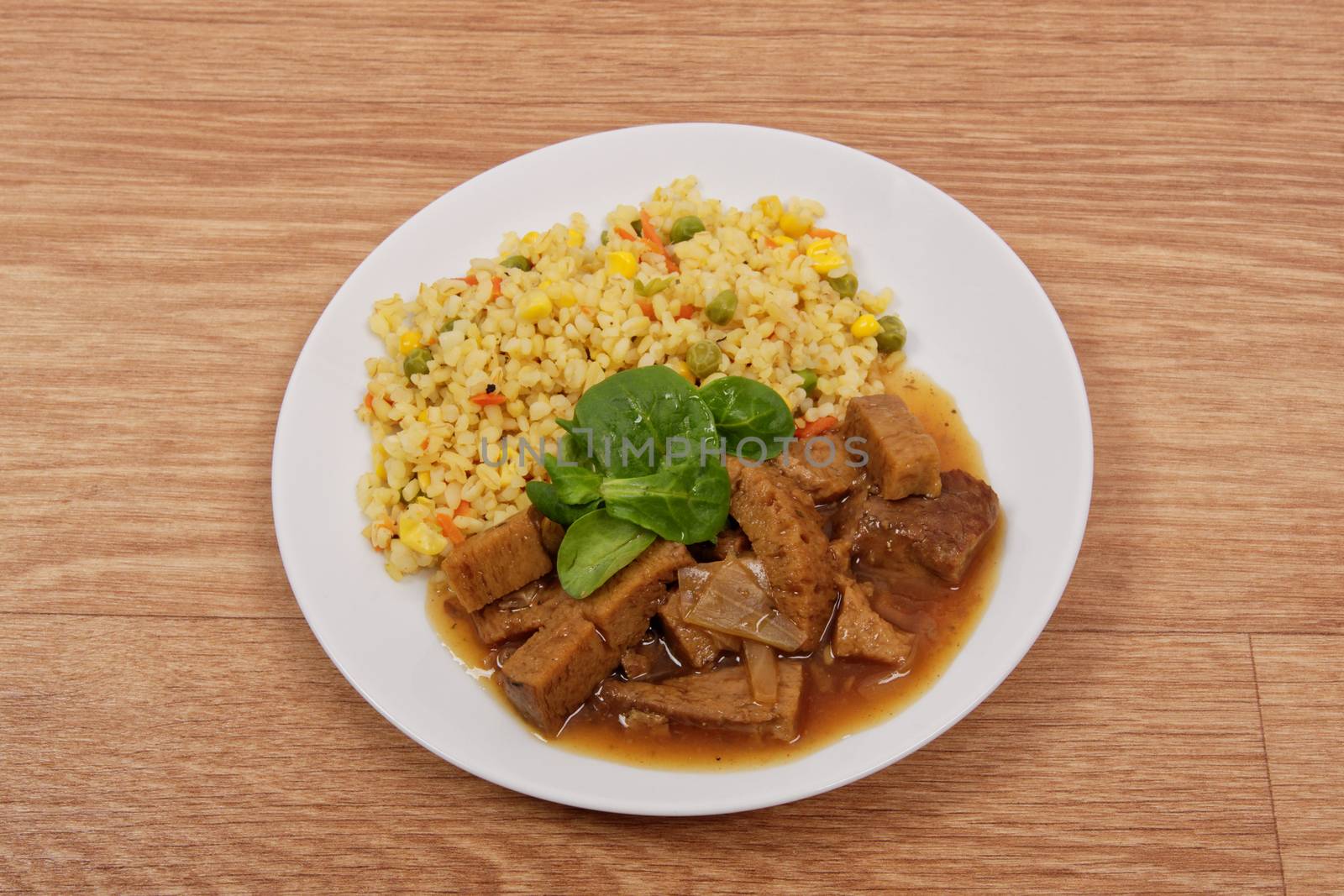 Tempeh with tomato sauce and millets on a wooden table