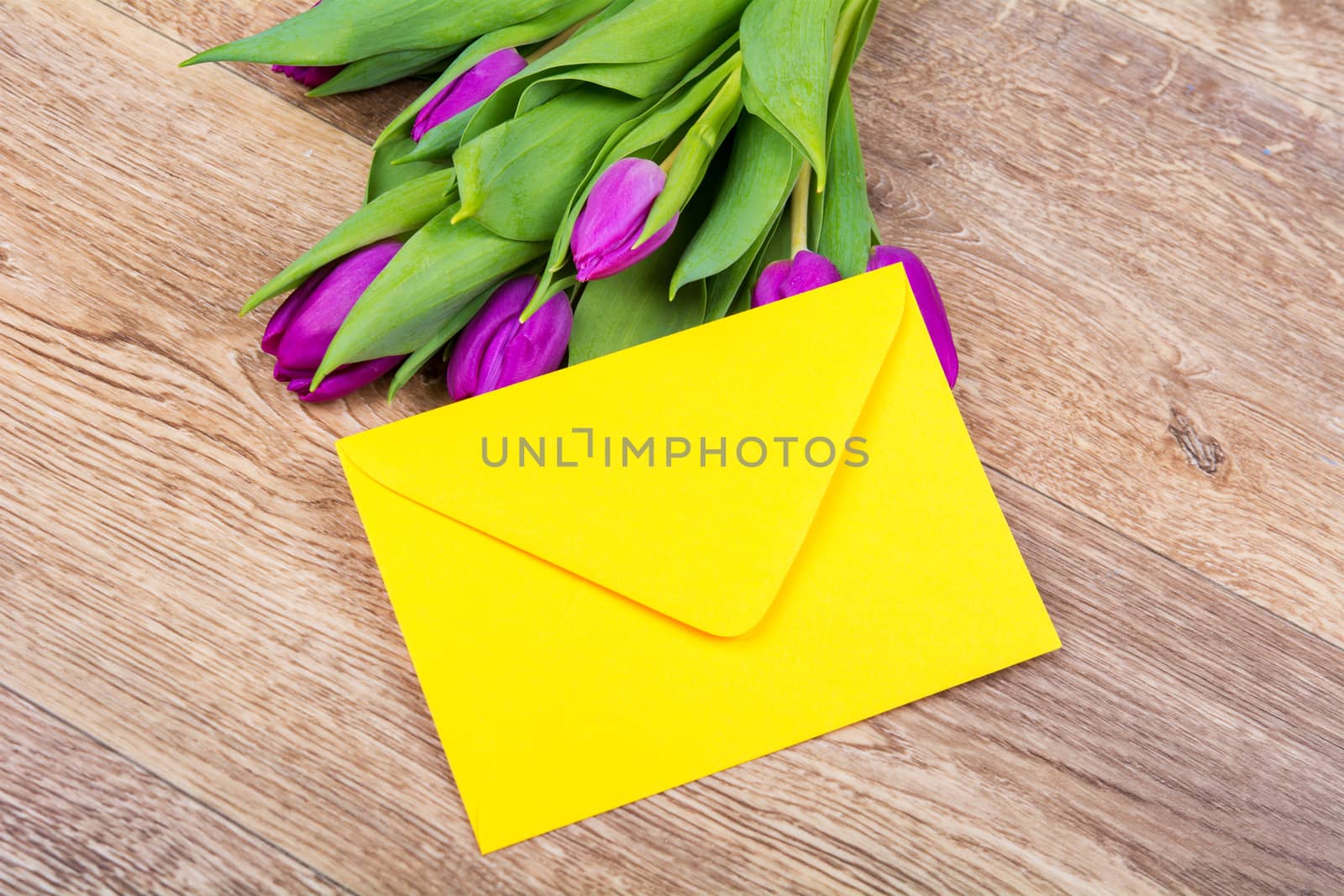 Yellow envelope with tulips on a wooden table