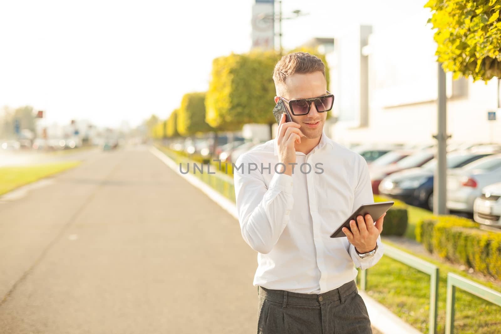 Businessman with mobile phone and tablet in hands by adamr